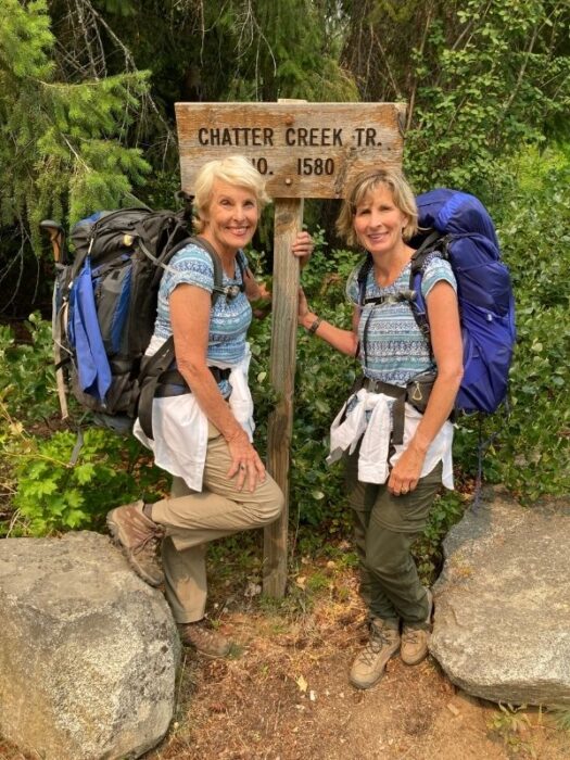 two women with backpacks at the Chatter Creek Trail signpost