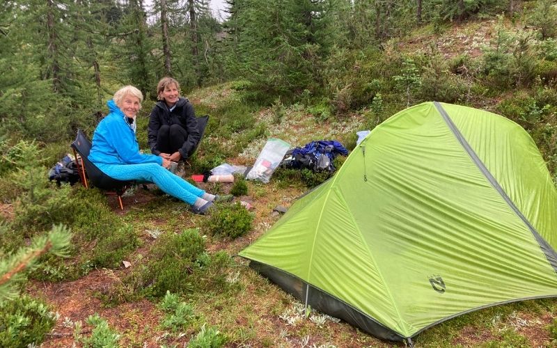 two women camping with green tent