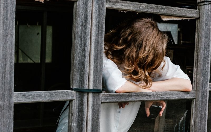 woman leaning out of open window in old barn, looking down