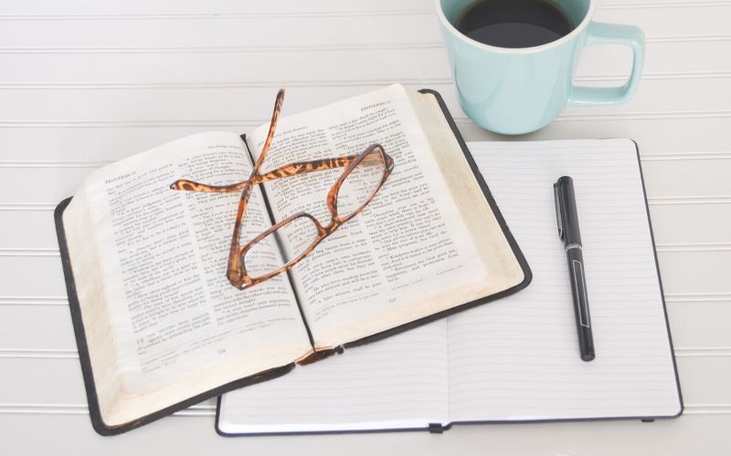 Bible with notebook, pen, glasses, and cup of coffee