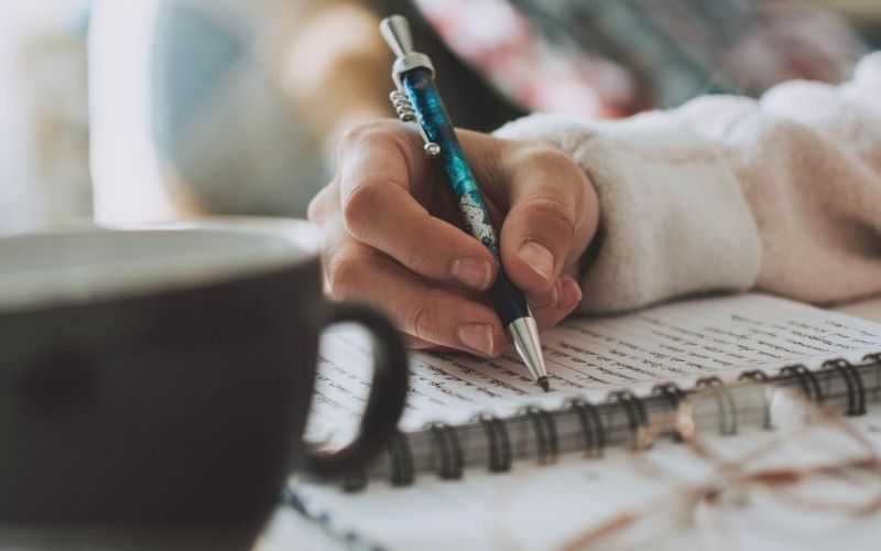 woman journaling with a cup of coffee