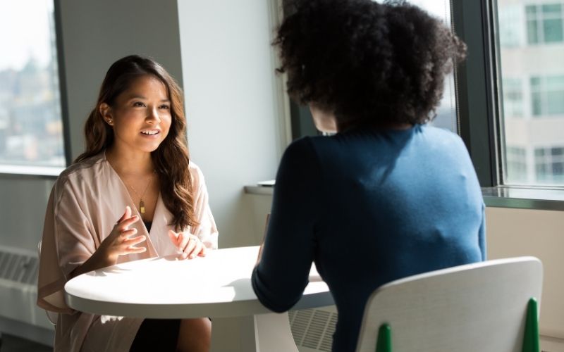 Two women sitting at a small table talking