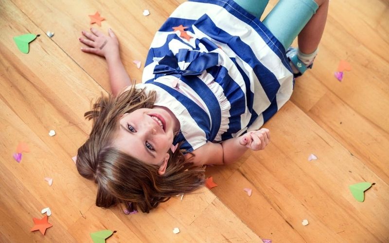 young girl on the floor, throwing paper confetti