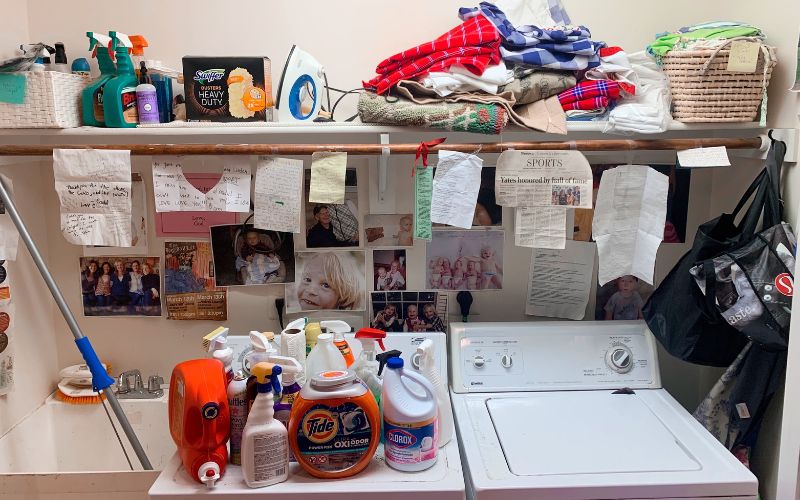 A laundry room with thank-you notes and photos taped to the wall.