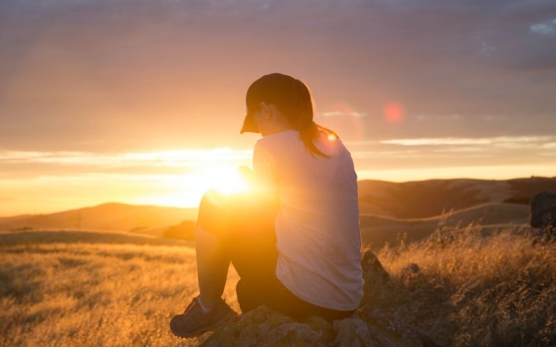 Woman praying in the mountains at sunset